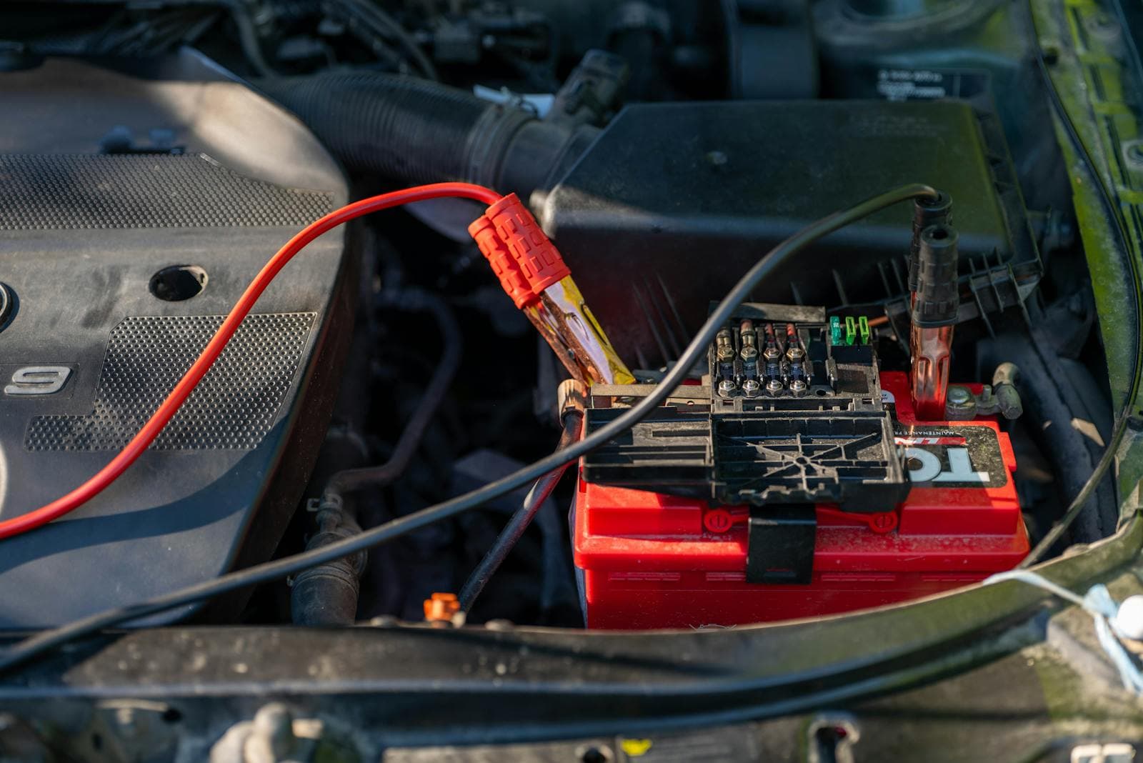 Jumper leads clamped to a car battery in an engine bay