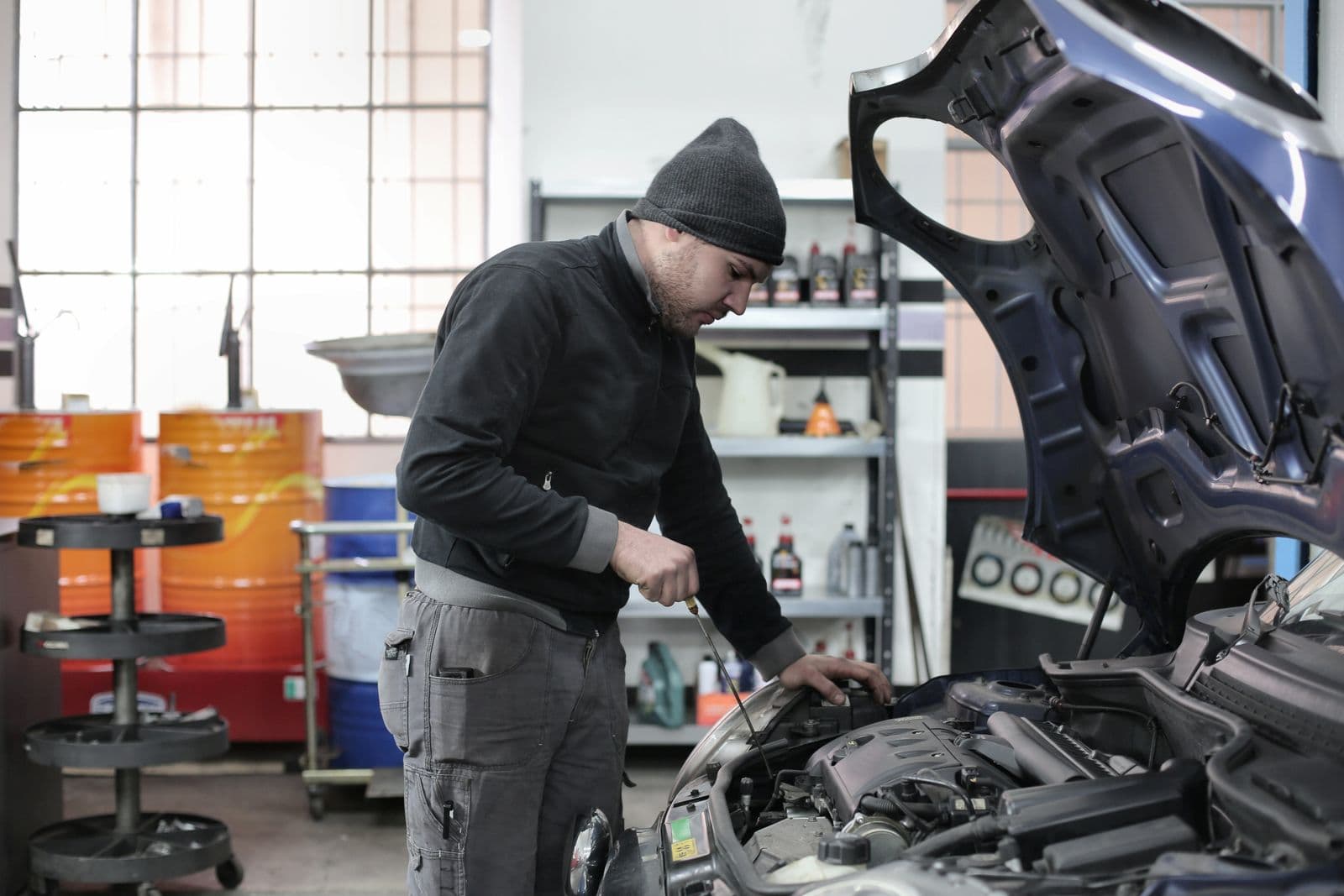 Mechanic checking the oil level on a dipstick with the bonnet up